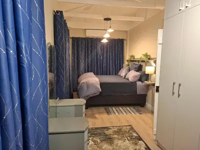 a bedroom with a bed and a blue curtain at Mukuru Okunene in Strand