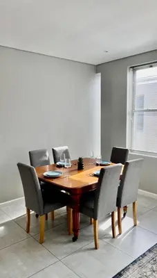 a dining room with a wooden table and chairs at The Madge Self Catering in Paarl