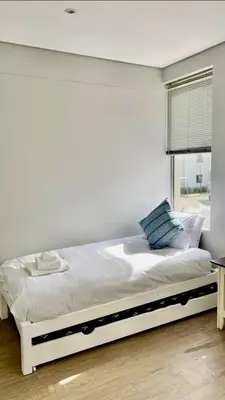a white bed in a room with a window at The Madge Self Catering in Paarl
