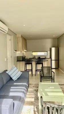 a living room with a blue couch and a kitchen at The Madge Self Catering in Paarl