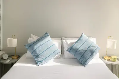 a white bed with blue and white pillows on it at The Madge Self Catering in Paarl