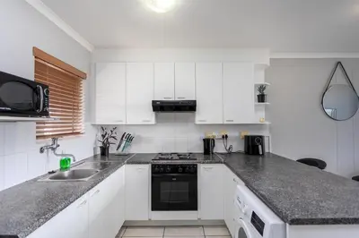 a white kitchen with a sink and a stove at Century on Lake B31 by CTHA in Cape Town