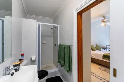 a bathroom with a sink and a shower and a bed at Century on Lake B31 by CTHA in Cape Town