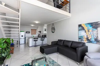 a living room with a black couch and a kitchen at Century on Lake B31 by CTHA in Cape Town