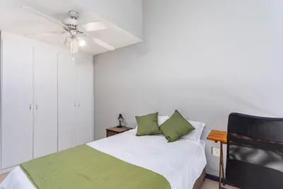 a bedroom with a bed with green pillows and a ceiling fan at Century on Lake B31 by CTHA in Cape Town