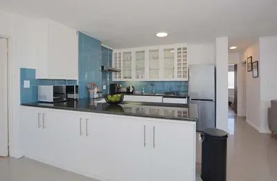 a kitchen with white and blue cabinets and a refrigerator at Ocean View B401 by CTHA in Bloubergstrand