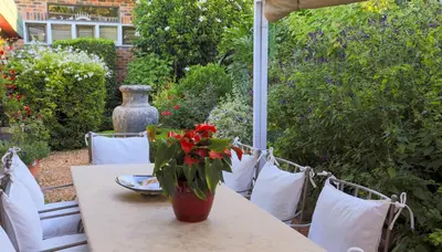 a table with a vase with red flowers on it at Kaniek - Guest Suite in Somerset West