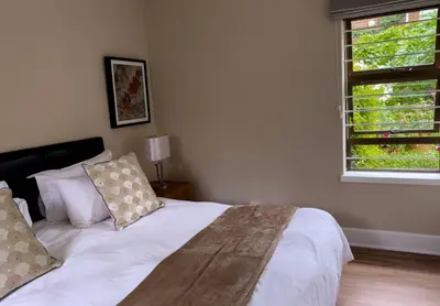 a white bed in a bedroom with a window at Kaniek - Guest Suite in Somerset West