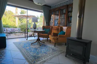 a living room with a fireplace and chairs and a stove at Kaniek - Guest Suite in Somerset West