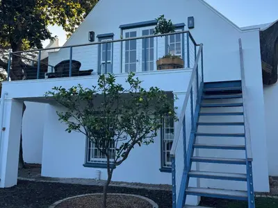 a staircase leading up to a white house with a tree at The Bothey House in Somerset West