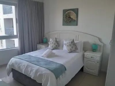 a bedroom with a white bed and a window at Sunset 786 Holiday Accommodation-Room 208 in Strand
