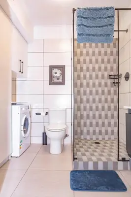 a bathroom with a toilet and a washing machine at La Savina On Lake 219 The Island Club in Cape Town