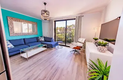 a living room with a blue couch and a tv at La Savina On Lake 219 The Island Club in Cape Town
