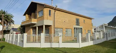 a brick house with a white fence at C-Onrus in Hermanus