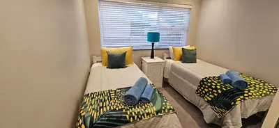 two twin beds in a room with a window at C-Onrus in Hermanus