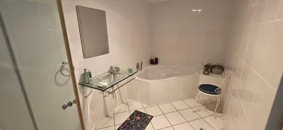 a white bathroom with a tub and a toilet at C-Onrus in Hermanus