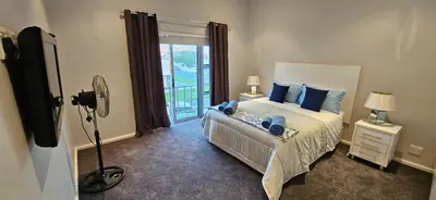 a bedroom with a bed with blue pillows and a window at C-Onrus in Hermanus