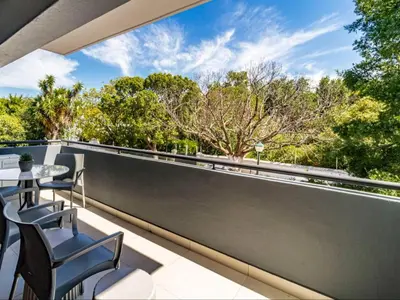a balcony with chairs and a view of trees at FamoHof Apartments in Stellenbosch