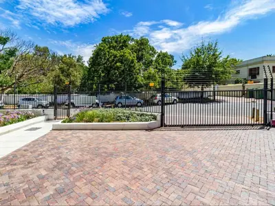 a black wrought iron gate with a brick driveway at FamoHof Apartments in Stellenbosch