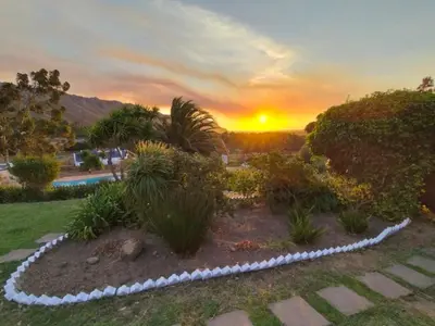 a garden with plants and a sunset in the background at Into the Sunset Manor in Gordonʼs Bay