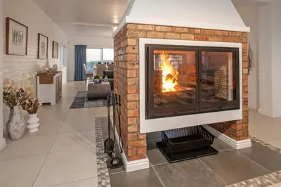 a fireplace with a fire in it in a living room at Vermont Vista - With Pool in Hermanus