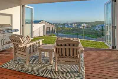 a patio with two chairs and a table on a deck at Vermont Vista - With Pool in Hermanus