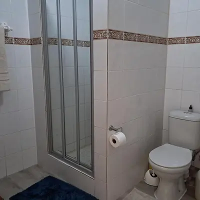 a bathroom with a toilet and a glass shower at Vermont Garden Cottage in Hermanus