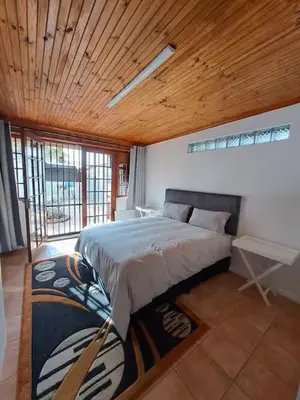 a bedroom with a large bed with a wooden ceiling at Azzure Apartments 4 sleeper Crawford in Cape Town