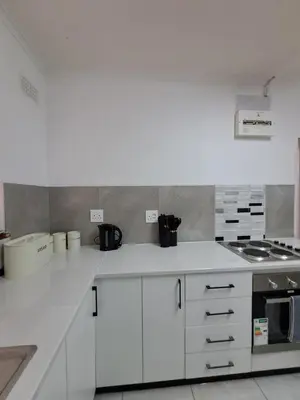 a kitchen with white cabinets and a stove at Azzure Apartments 6 sleeper Crawford in Cape Town