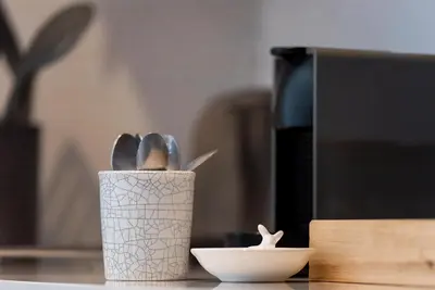 a cup with spoons and a bowl on a counter at Arch Window garden apartment in Stellenbosch