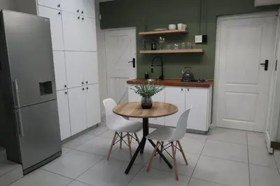a kitchen with a table and chairs and a refrigerator at 64 On Forest in Cape Town