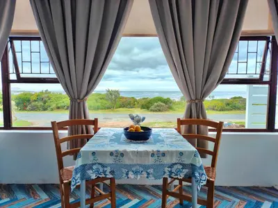 a table with a bowl of fruit on it in front of a window at Sand Sittie in Sandbaai