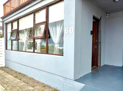 a white building with a door and a window at Sand Sittie in Sandbaai
