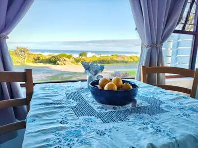 a bowl of fruit on a table with a view of the ocean at Sand Sittie in Sandbaai