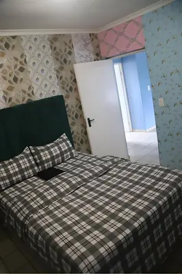 a bedroom with a bed with a plaid blanket and a door at Browns villa in Cape Town