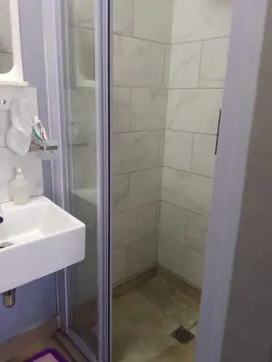 a shower with a glass door next to a sink at Camdene Guesthouse in Cape Town