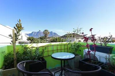 a patio with a table and chairs and plants at Camdene Guesthouse in Cape Town