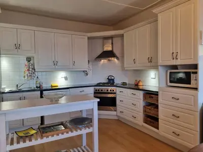 a kitchen with white cabinets and a white counter top at 'Top Flat' Apartment with Easy Beach Access, Sea front sleeps 5 in Gordonʼs Bay