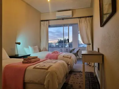 two beds in a hotel room with a window at 'Top Flat' Apartment with Easy Beach Access, Sea front sleeps 5 in Gordonʼs Bay