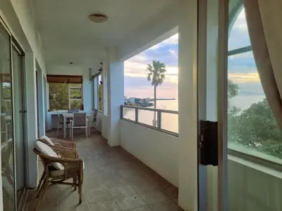 a room with a balcony with a view of the ocean at 'Top Flat' Apartment with Easy Beach Access, Sea front sleeps 5 in Gordonʼs Bay