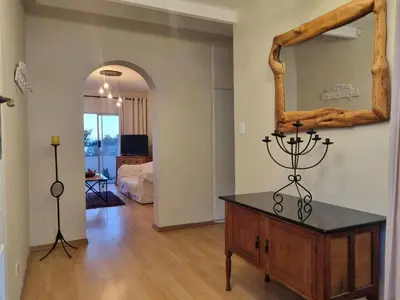 a living room with a table and a mirror at 'Top Flat' Apartment with Easy Beach Access, Sea front sleeps 5 in Gordonʼs Bay