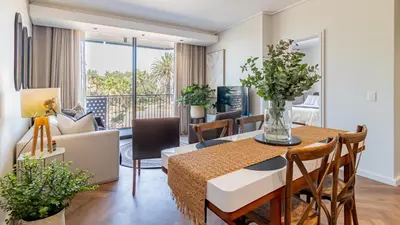 a dining room and living room with a table and a couch at Table Mountain View Apartment in Cape Town