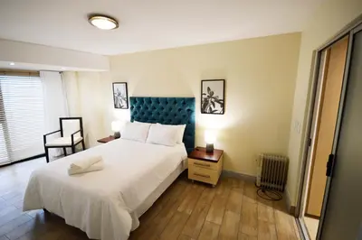 a bedroom with a large white bed with a blue headboard at 402 Ocean View in Strand