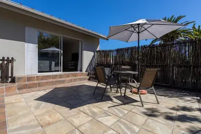 a patio with a table and chairs and an umbrella at Bed On Boucher in Durbanville