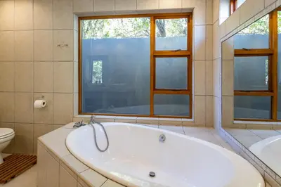 a large bathroom with a tub and a toilet at Bed On Boucher in Durbanville