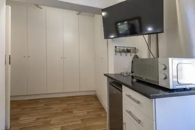 a kitchen with white cabinets and a microwave at Bed On Boucher in Durbanville