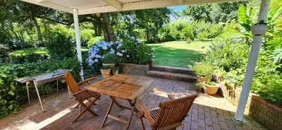 a patio with a wooden table and chairs under an umbrella at Sunkiss Cottage on Mount Joy Farm in Stellenbosch