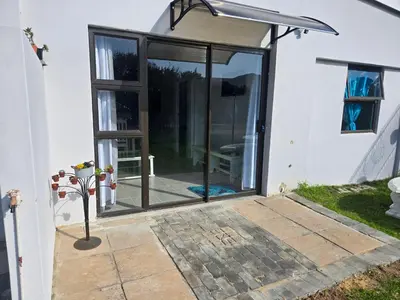 a sliding glass door of a house with a patio at Cozy Cottage in Hermanus