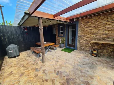a patio with a wooden table and a bench at LieBling Place in Cape Town