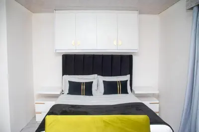 a bedroom with a large bed with a yellow blanket at Optimum Stay Self Catering Accommodation - Junior Suite in Parow